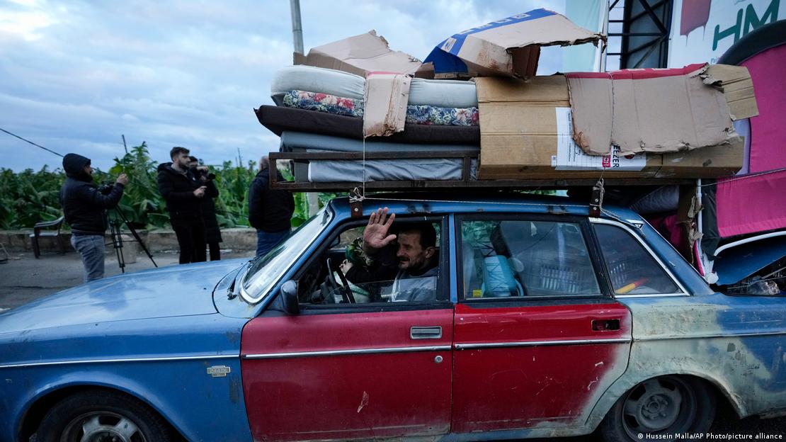 حزب اللہ اور اسرائیل کے درمیان جنگ بندی کے نافذ ہونے کے بعد جنوبی لبنان کے شہر صور میں ایک شخص اپنے گاؤں واپس جاتے ہوئے اپنی گاڑی پر سامان لادے ہاتھ ہلاتا ہوا نظر آ رہا ہے