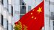 Bandeira da China com prédio envidraçado ao fundo
