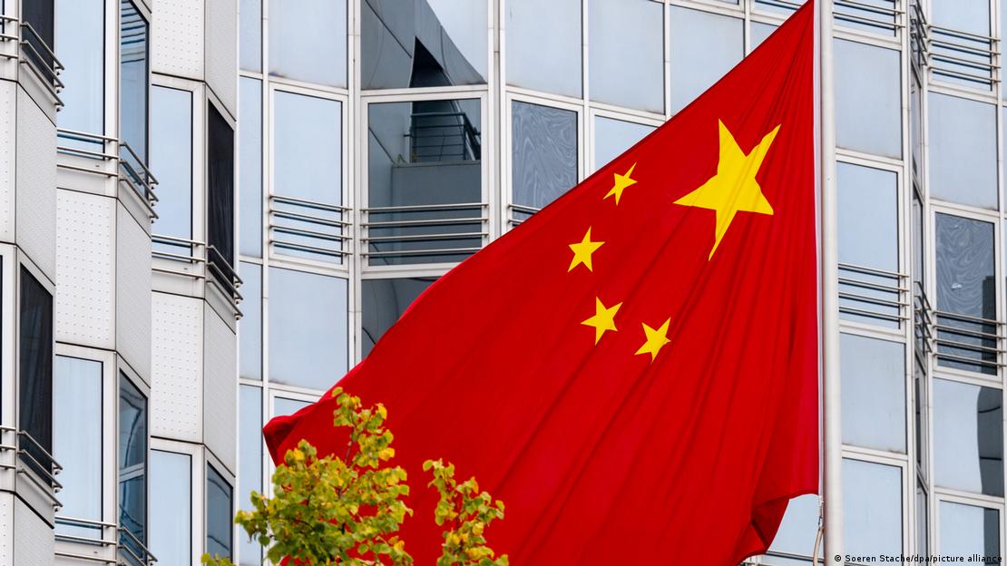 Bandeira da China com prédio envidraçado ao fundo Bandeira da China com prédio envidraçado ao fundo