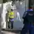 A contractor cleans anti-Israel graffiti as a police officer looks on, on December 11, 2024.