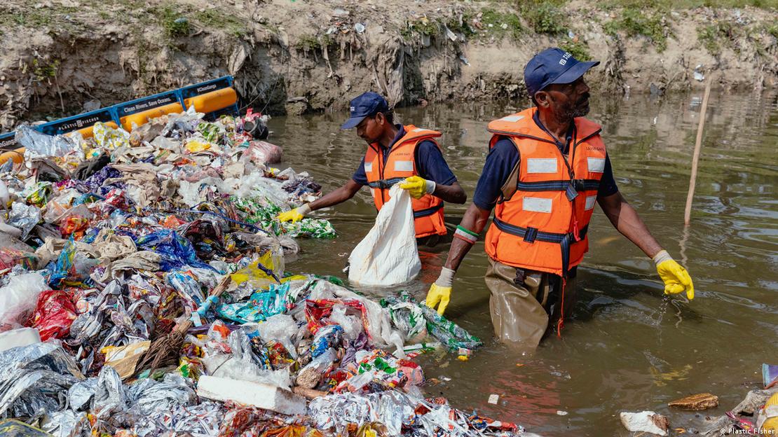 Dos personas recogiendo plásco del agua.