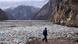 A man walks on a beach absolutely covered in plastic waste