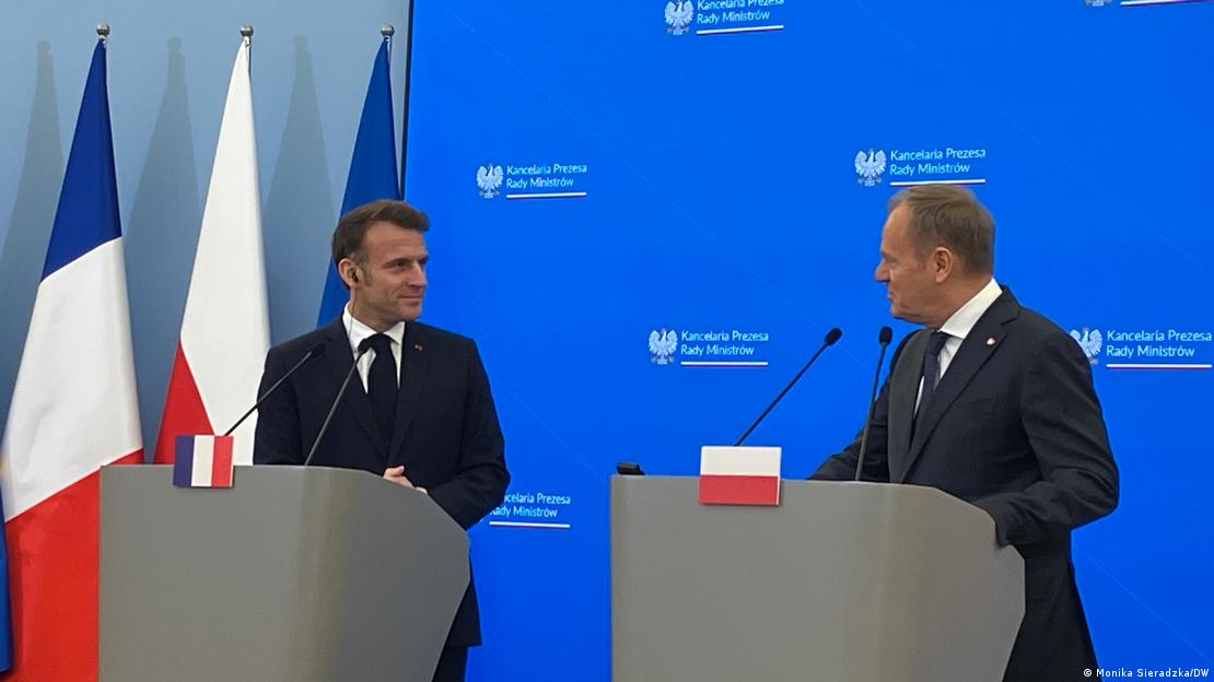 Der französische Präsident Emmanuel Macron (links) und der polnische Premierminister Donald Tusk stehen an zwei Rednerpulten, die jeweils mit den Nationalfahnen der beiden Länder Frankreich und Polen markiert sind. Sie wenden sich einander zu, während Tusk ins Mikrofon spricht und Macron mit einem Ohrhörer im Ohr zuhört Der französische Präsident Emmanuel Macron (links) und der polnische Premierminister Donald Tusk stehen an zwei Rednerpulten, die jeweils mit den Nationalfahnen der beiden Länder Frankreich und Polen markiert sind. Sie wenden sich einander zu, während Tusk ins Mikrofon spricht und Macron mit einem Ohrhörer im Ohr zuhört