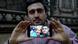 Anas Modamani mostra sua selfie de 2015 com a então chanceler Angela Merkel em tela de celular