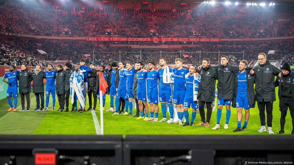 Magdeburg's players stand in a line with their arms around each other