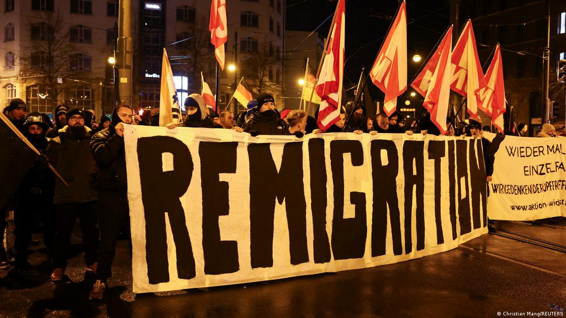 Manifestação da extrema direita contra imigração em Magdeburg, na Alemanha. A imagem noturna mostra um painel de vários metros com a palavra "Remigration" ("remigração", em tradução livre), sendo segurada pelos manifestantes