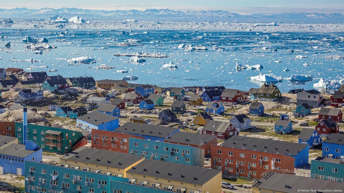 Panoramë e qytetit bregdetar në Groenlandë Ilulissat - deti i mbuluar nga akullnaja dhe shtëpitë në bregdet