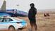 Vista de los restos del avión de Azerbaijan Airlines (AZAL) en Aktau, Kazajistán, con un agente de seguridad de pie frente al fuselaje siniestrado.