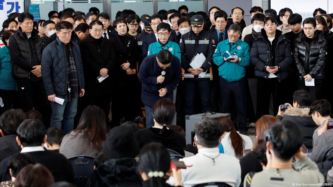 Familiares observam oficial da Jeju Air se curvar em pedido de desculpa Familiares observam oficial da Jeju Air se curvar em pedido de desculpa