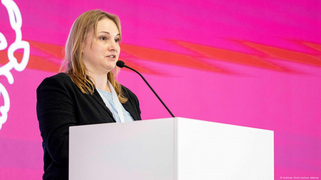 Жена во темно палто (Олха Решетилова, ополномоштеничка на претседателот Зеленски за заштита на правата на припадници на војската и на нивните семејства) стои на говорница и зборува Жена во темно палто (Олха Решетилова, ополномоштеничка на претседателот Зеленски за заштита на правата на припадници на војската и на нивните семејства) стои на говорница и зборува