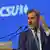 Bavaria's State Premier Markus Söder speaking at a lectern with his left hand raised