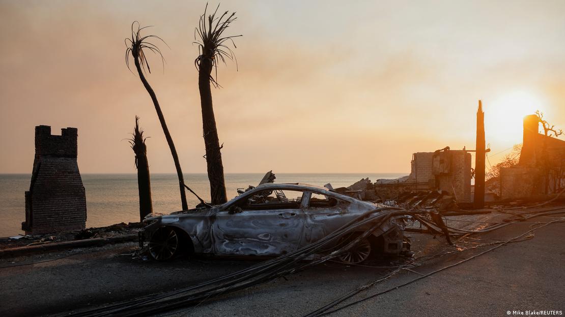 Carro queimado ao lado de casas à beira-mar em ruínas. Carro queimado ao lado de casas à beira-mar em ruínas.