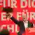 German Chancellor Olaf Scholz holding bouquet in front of podium reading "Mehr fuer dich, besser fuer Deutschland" slogan at party congress