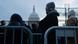 People wearing scarves and caps in the foreground, with the US Capitol in the background People wearing scarves and caps in the foreground, with the US Capitol in the background