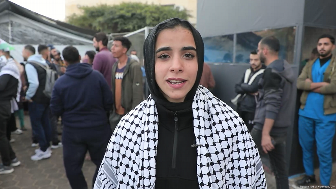 Malak Hussain mira a la cámara. Detrás de ella hay muchos hombres. Malak Hussain mira a la cámara. Detrás de ella hay muchos hombres.