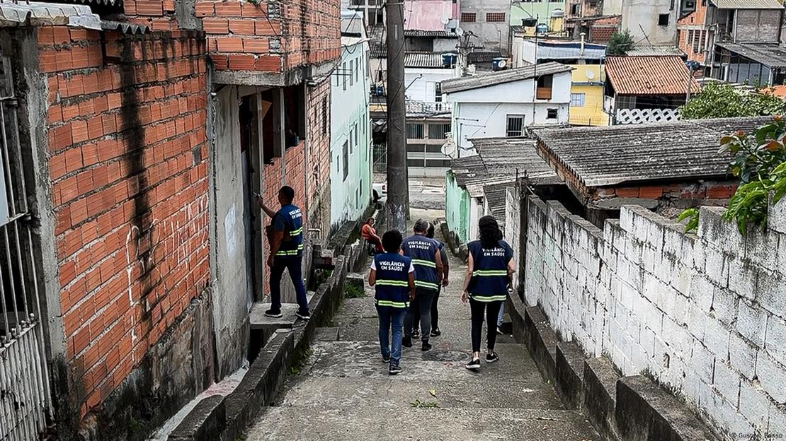 Grupo de funcionários sanitários uniformizados em rua de comunidade de São Paulo