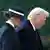 Melania, wearing suit and wide-brimmed hat, walks alongside husband Donald Trump