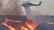 A helicopter drops water on a fire A helicopter drops water on a fire