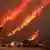 Flames rise behind vehicles as the Hughes Fire burns in Castaic Lake, California, US January 22, 2025