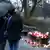 Two people in black hold an umbrella at a bench covered in candles commemorating the victims of a fatal stabbing in Aschaffenburg, Germany