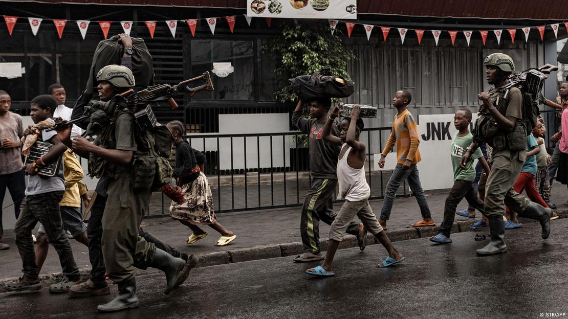 Soldados fuertemente armados caminan junto a civiles por la calle. 