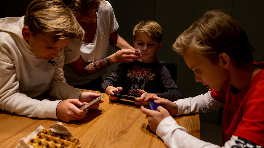 Tres niños meriendan sin separarse de sus teléfonos celulares. Tres niños meriendan sin separarse de sus teléfonos celulares.