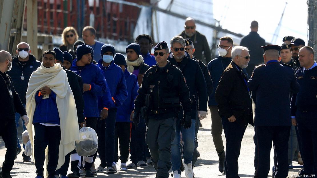 Anija që transporton migrantë në Shqipëri. Ne foto police dhe migrante pas tyre.
