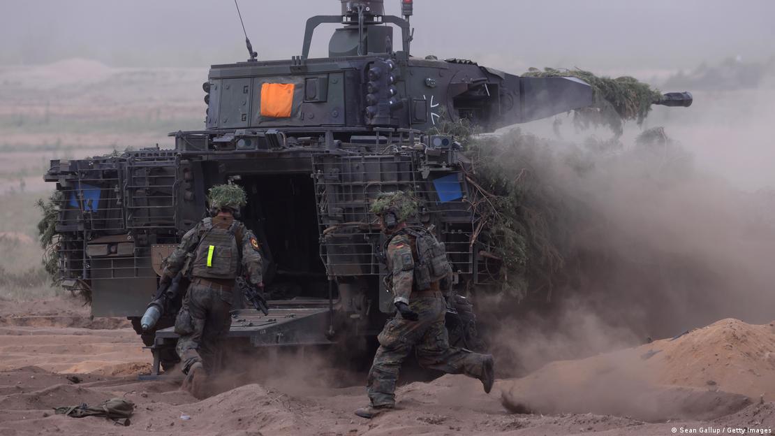 Bundeswehrsoldaten in Kampfausrüstung laufen auf ein Militärfahrzeug zu Bundeswehrsoldaten in Kampfausrüstung laufen auf ein Militärfahrzeug zu