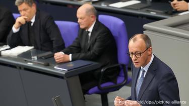 Ο Friedrich Merz μιλά στη συζήτηση της Bundestag. Ο Olaf Scholz και ο Robert Habeck είναι ορατοί στο βάθος