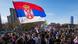 Hundreds of young men and women — some carrying banners and Serbian flags — walk along a street in Belgrade in the sunshine Hundreds of young men and women — some carrying banners and Serbian flags — walk along a street in Belgrade in the sunshine