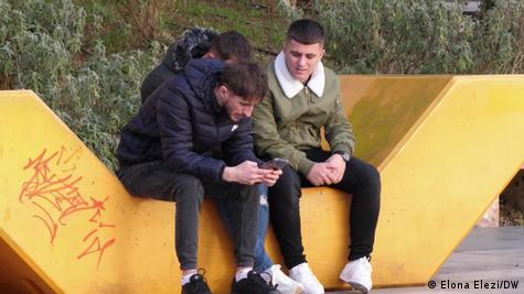 Të rinj të ulur në stol në sheshin "Skënderbej" në Tiranë, me telefona në duar Të rinj të ulur në stol në sheshin "Skënderbej" në Tiranë, me telefona në duar
