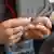 A man takes a pill with a glass of water, only his hands and the glass are seen