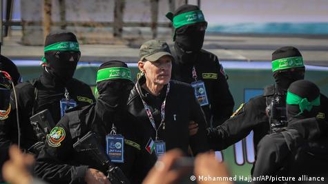 El rehén israeloestadounidense, con gorra, entre viarios milicianos armados y encapuchados. El rehén israeloestadounidense, con gorra, entre viarios milicianos armados y encapuchados.