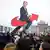 At a protest in Berlin, a sign shows Chancellor Friedrich Merz riding the red swoop arrow featured in the AfD logo