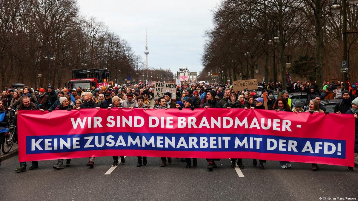 People marching down a street in central Berlin carrying a banner that reads ''We are the firewall. No collaboration with the AfD