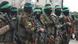 Militantes do Hamas vestindo uniforme militar, capuz preto, faixa verde na testa e metralhadora em mãos 