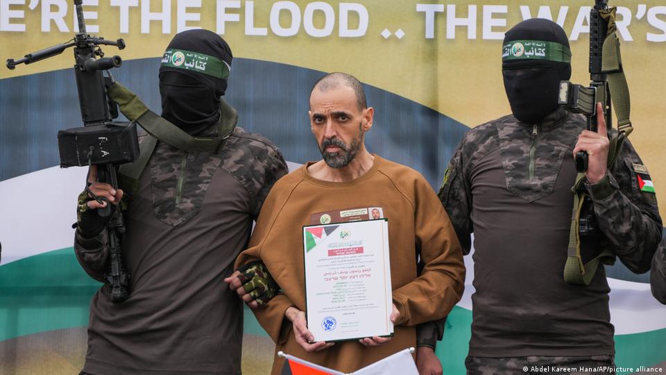 Eli Sharabi en el podio escoltado por combatientes de Hamás antes de ser entregado a la Cruz Roja (08.02.2025)