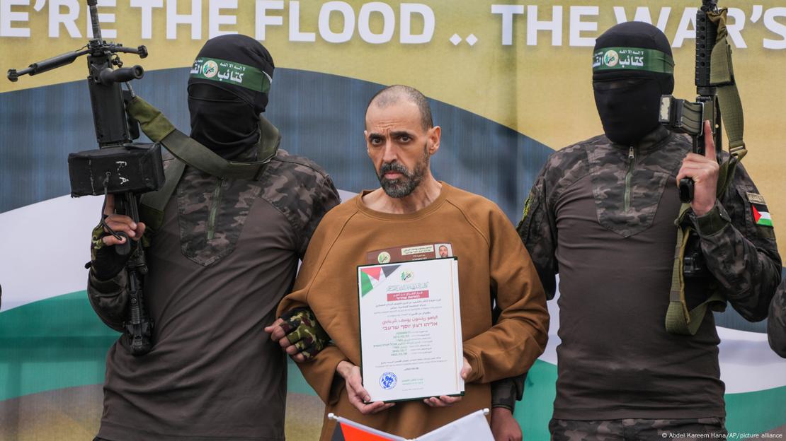 Eli Sharabi en el podio escoltado por combatientes de Hamás antes de ser entregado a la Cruz Roja (08.02.2025)