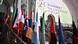 Bandeiras de países participantes em escadaria na entrada da cúpula de IA em Paris