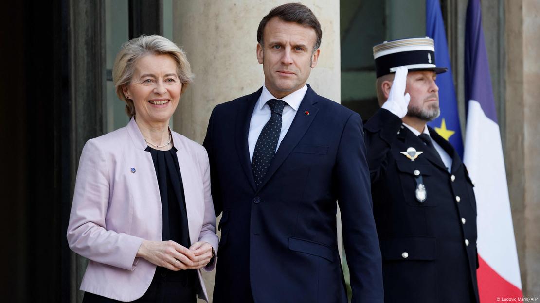 Ursula von der Leyen e Emmanuel Macron, com guarda fazendo continência ao fundo