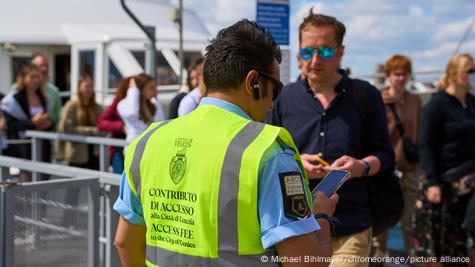 Kontrolle në platformën e zbarkimit të anijeve në Venecia, një punonjës i bashkisë kontrollon biletat elektronike në smartphone, përpara tij qendrojnë turistët.