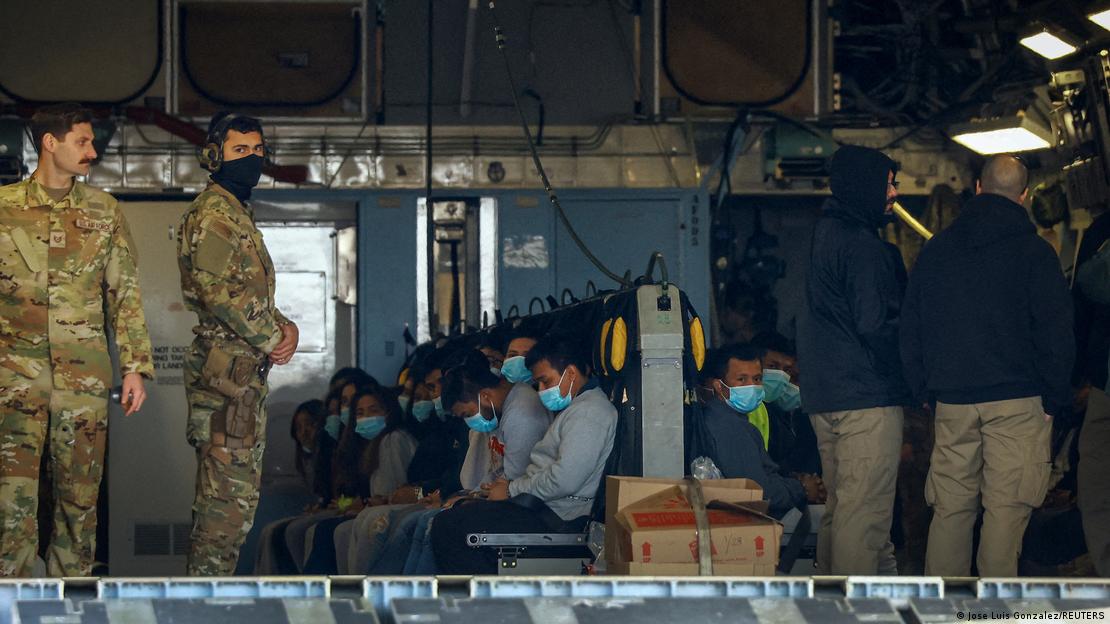 Agentes da imigração observam migrantes acomodados em avião da Força Aérea americana em voo de deportação