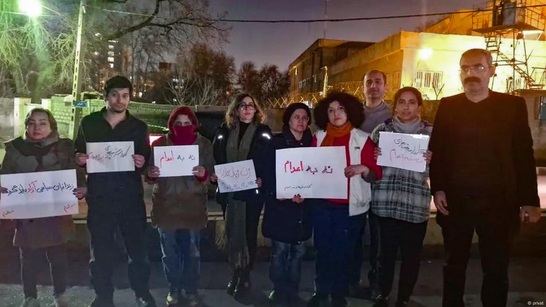 Varias personas, mujeres y hombres, protestan con carteles contra las ejecuciones, delante de la prisión de Evin, en Teherán.