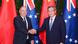 Cook Islands Prime Minister Mark Brown shakes hands with Chinese Premier Li Qiang in front of Cook Islands and Chinese flags