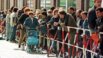 Flüchtlinge warten in einer langen Schlange vor einer Ausländerbehörde. (Foto: AP)