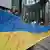 Protesters hold up a long Ukrainian flag with red lines on it, symbolizing loss of life in Ukraine
