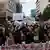 Young men and women in a crowd chant slogans and hold up banners and signs with messages in Greek, one of which reads 'I have no oxygen'