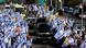 People hold Israeli flags as a funeral convoy of black limousines makes its way down a road in Ashkelon, Israel