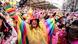 Jubelnde bunt verkleidete Menschen, im Vordergund eine Peron in einem Regenbogenfarbenen Fantasiekostüm. Jubelnde bunt verkleidete Menschen, im Vordergund eine Peron in einem Regenbogenfarbenen Fantasiekostüm.