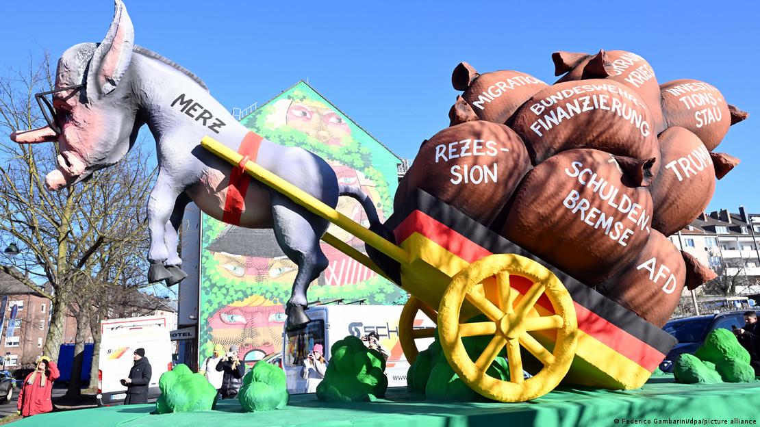 Deutschland Düsseldorf 2025 | Rosenmontagszug | Ein Motivwagen zeigt den Unions-Kanzlerkandidaten Friedrich Merz als Esel, der einen Wagen ziehen will. Die Ladung sind große Säcke, auf denen Rezession, Migration, Schuldenbremse, AfD, Trump, Bundeswehr-Finanzierung, Investitionsstau steht. Die Ladung ist zu schwer, deswegen hängt der Esel in der Luft. Deutschland Düsseldorf 2025 | Rosenmontagszug | Ein Motivwagen zeigt den Unions-Kanzlerkandidaten Friedrich Merz als Esel, der einen Wagen ziehen will. Die Ladung sind große Säcke, auf denen Rezession, Migration, Schuldenbremse, AfD, Trump, Bundeswehr-Finanzierung, Investitionsstau steht. Die Ladung ist zu schwer, deswegen hängt der Esel in der Luft.